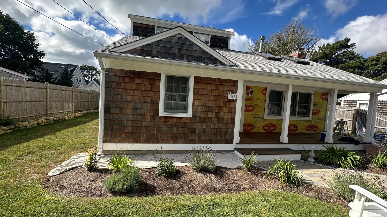 Cedar shingle siding replacement in progress in Dennis, MA, weather barrier exposed before new shingles go on